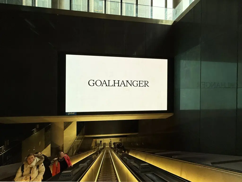 Large format digital screen above escalators in a London Underground station